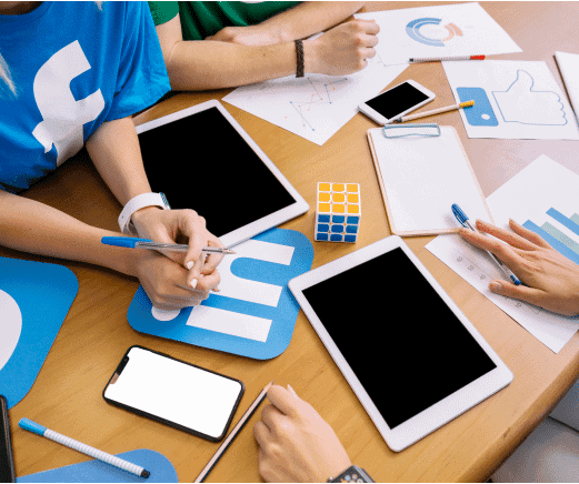 People collaborating at a table with tablets, charts, and a LinkedIn logo