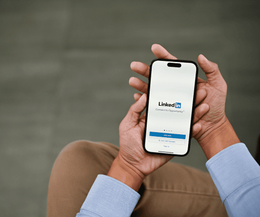Person holding a smartphone displaying the LinkedIn login screen