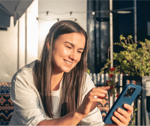 Woman smiling while browsing social media on a smartphone outdoors