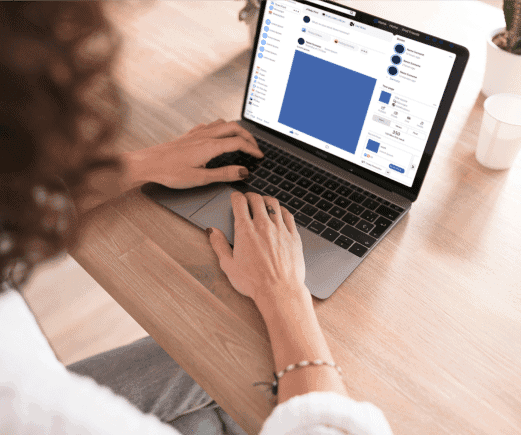 Hands using a laptop on a desk with a social media dashboard displayed on the screen